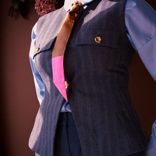Gray pinstripe vest with the brown and pink pinstriped Sable Wiles Silk twilly scarf by The Line Atelier styled as a tie on a model against a brown background