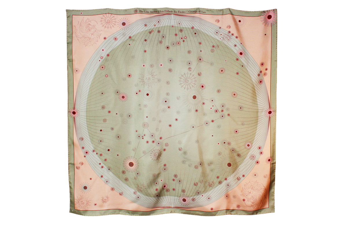 A square silk scarf featuring a celestial design with a large central pale green circle containing stars and the Leo constellation, surrounded by a peach-pink border and a muted sage green edge.