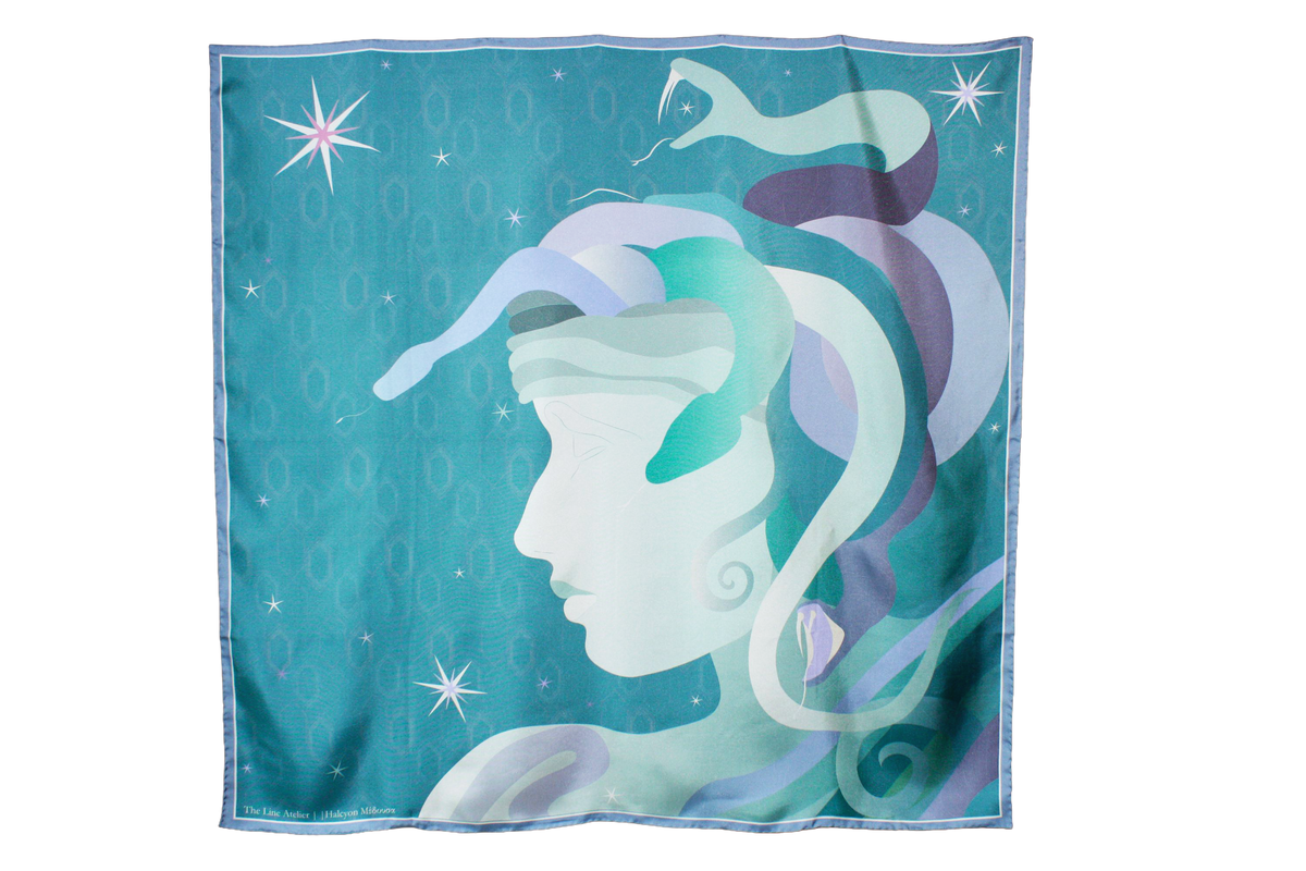 A large square silk scarf, Halcyon Medusa by The Line Atelier, featuring a stylized profile of a Medusa's face with flowing snake hair in shades of teal, purple, and white, set against a starry turquoise background.