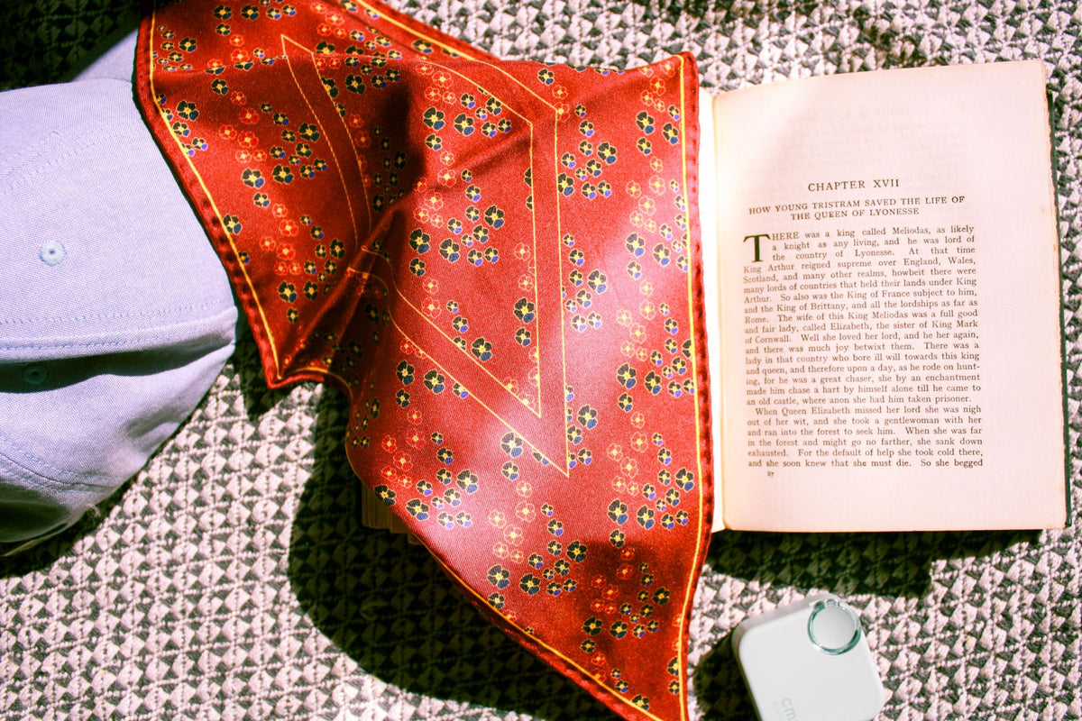 Red silk scarf over vintage book and a hat