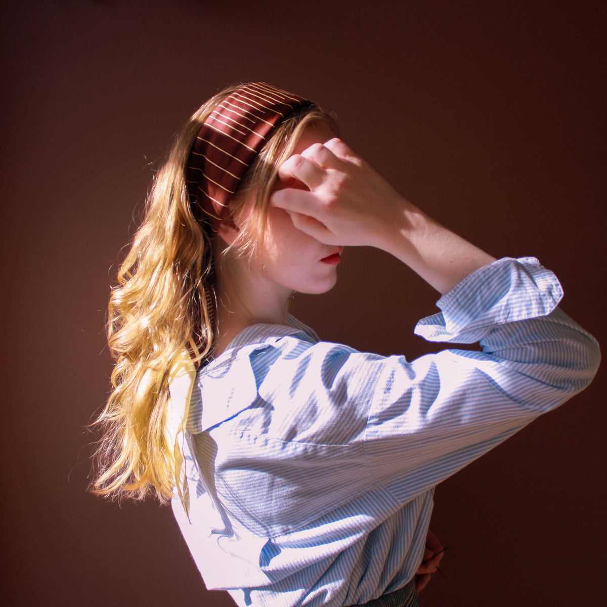 Model wearing the brown and pale gold striped large silk scarf square Rogues Equilibrium by The Line Atelier as a head band