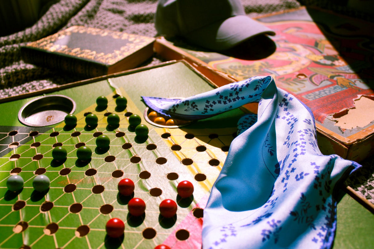 Close-up of a board game with checkers and the luminous blue silk scarf Sky Garden..