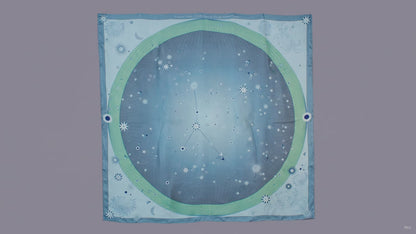 A square scarf featuring a celestial design with a light blue starry sky, a green ring, and the Cancer constellation patterns, hanging on a brown wall.
