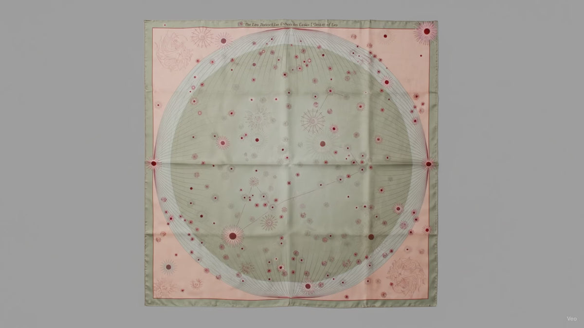 A square silk scarf featuring a celestial design with a large central pale green circle containing stars and the Leo constellation, surrounded by a peach-pink border and a muted sage green edge.
